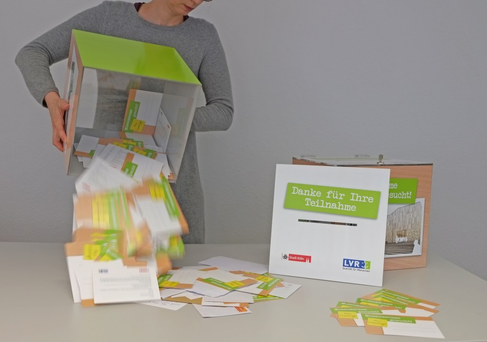 Eine Frau leert eine Box mit vielen Postkarten.