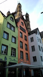 Drei bunt bemalte, schmale Häuser mit spitzen Dächern in der Kölner Altstadt.
