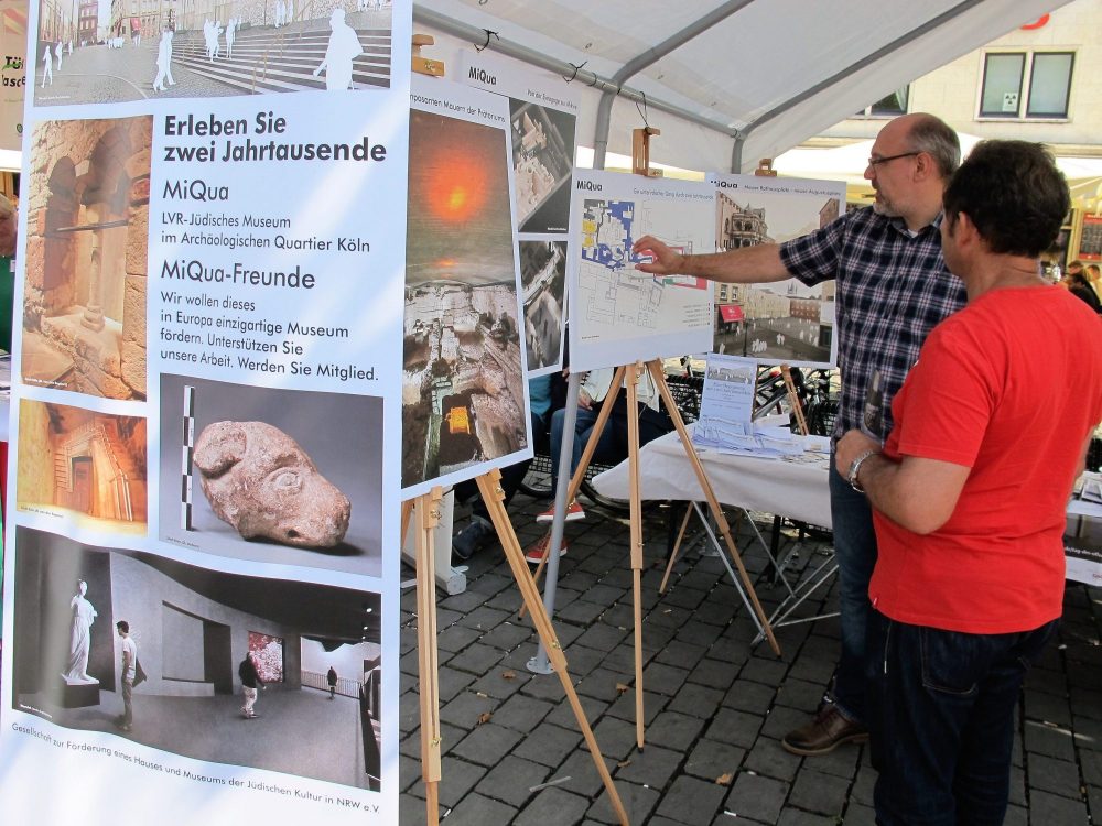 Ein Mann zeigt auf einen Plan, der sich auf einer Staffelei befindet.