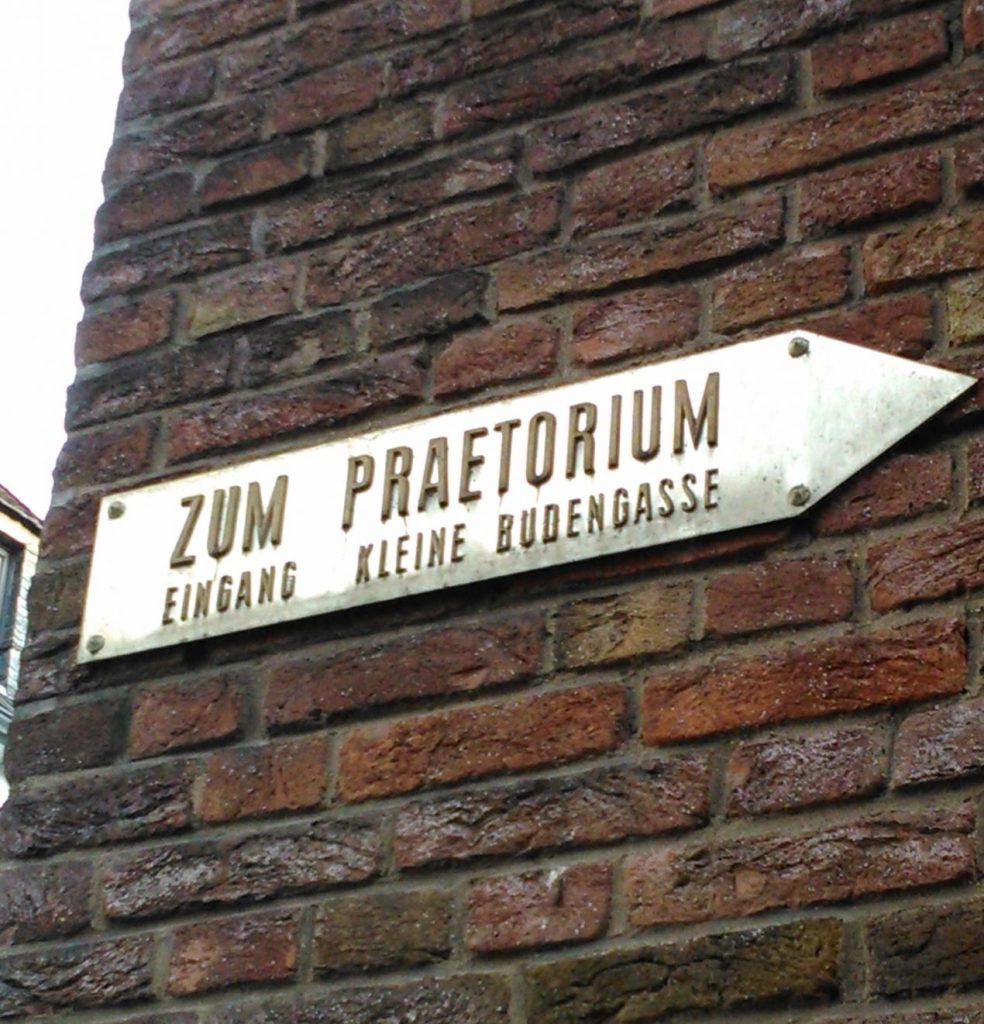 Hinweisschild zum Eingang Kleine Budengasse, angebracht an einer Hausfassade.