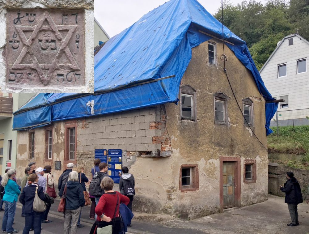 Besuchergruppe vor einem Gebäude. Am linken oberen Bildrand ist das Foto des Chuppa-Steins einmontiert.