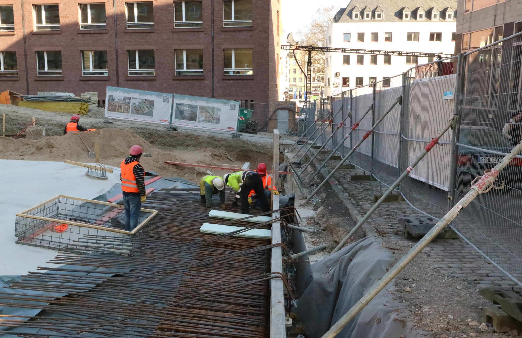 Drei Arbeiter montieren Stahlgeflecht auf der Baustelle des MiQua