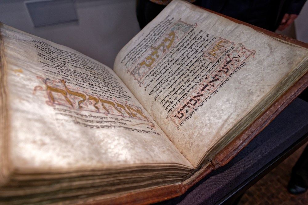 Der Amsterdam Machsor, eine mittelalterliche Prachthandschrift aus dem 13. Jahrhundert, liegt aufgeschlagen auf einer Buchstütze. Die geschmückten und verzierten Buchstaben, vor allem in Gold, stechen besonders hervor.