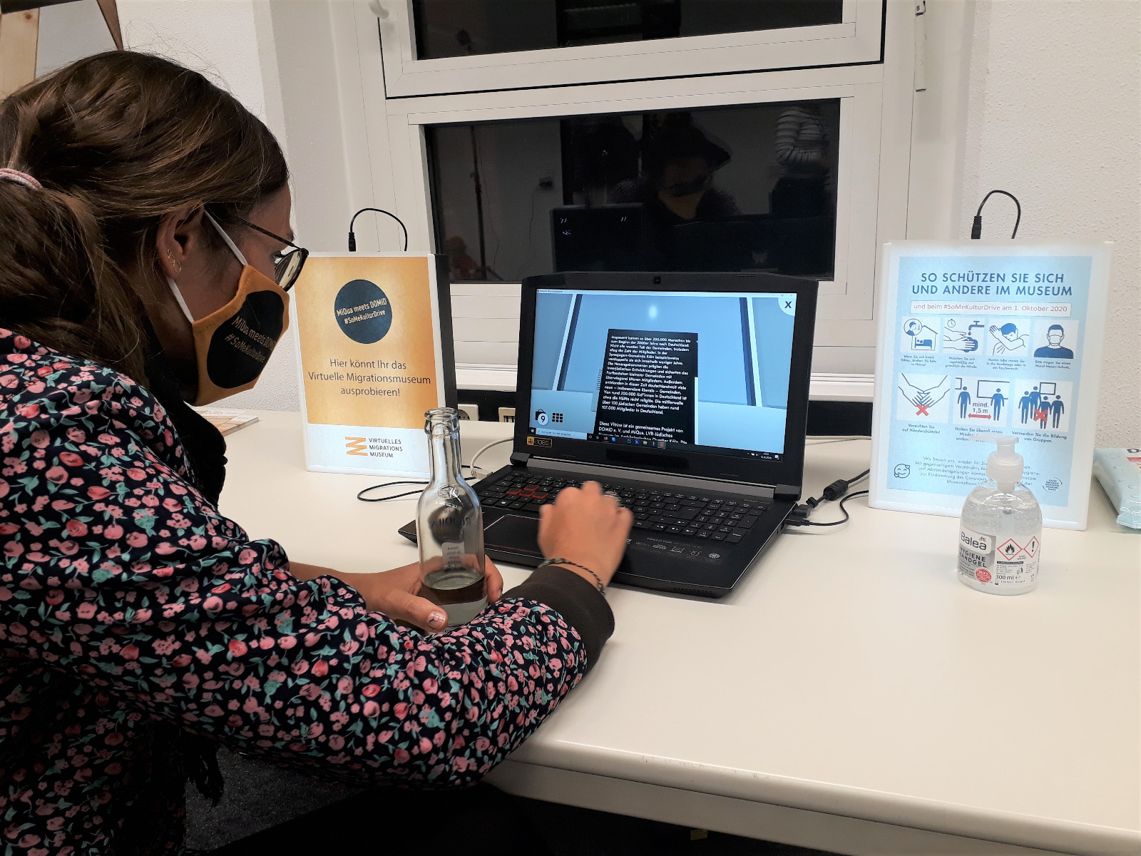 Eine Teilnehmerin sitzt an einem der Tische und testet die Anwendung an einem Laptop.