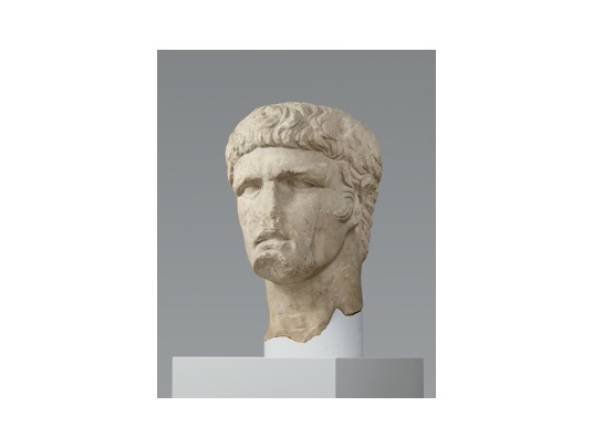 Büste des Kaisers Domitian: Kopf auf Halterung vor grauem Hintergrund.