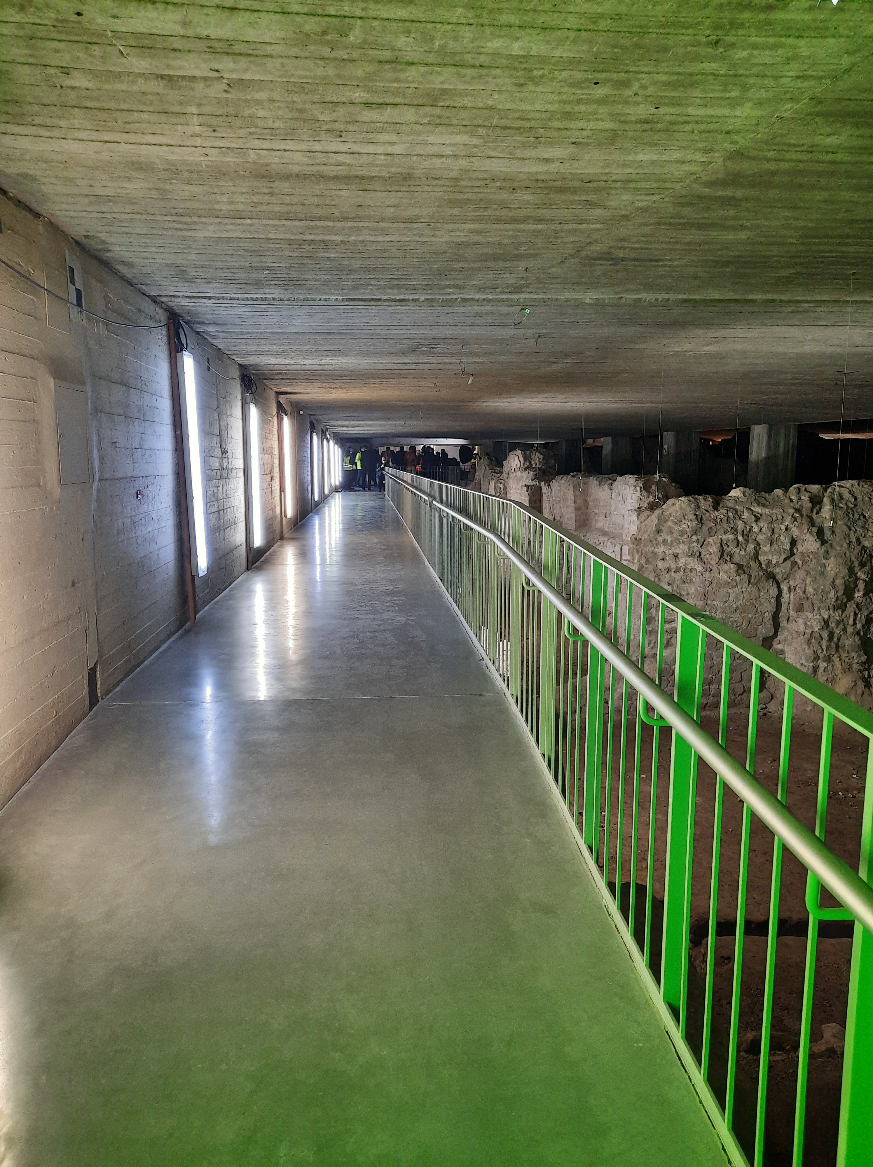 Blick in das Praetorium. Am Ende des Stegs für Besucher*innen steht eine kleine Menschenmenge. Rechts im Bild: archäologische Befunde des römischen Statthalterpalastes.