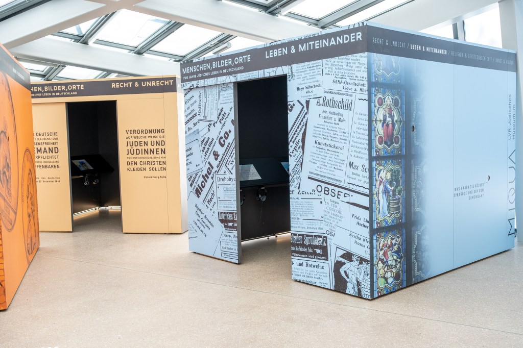 Drei begehbare Ausstellungswürfel unter einem hellen Glasdach