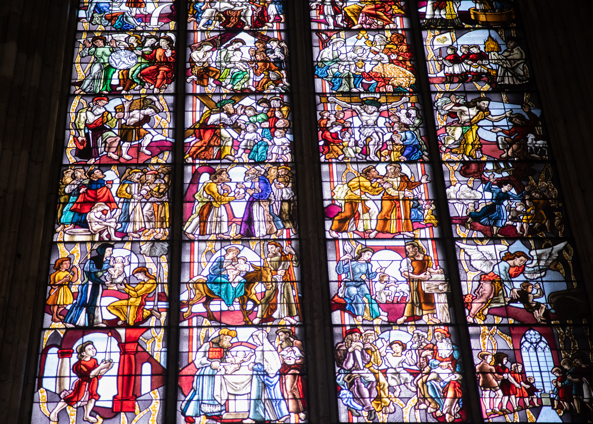 Detailaufnahme eines Kirchenfensters, in dem Motive des Alten und des Neuen Testaments gegenübergestellt sind.