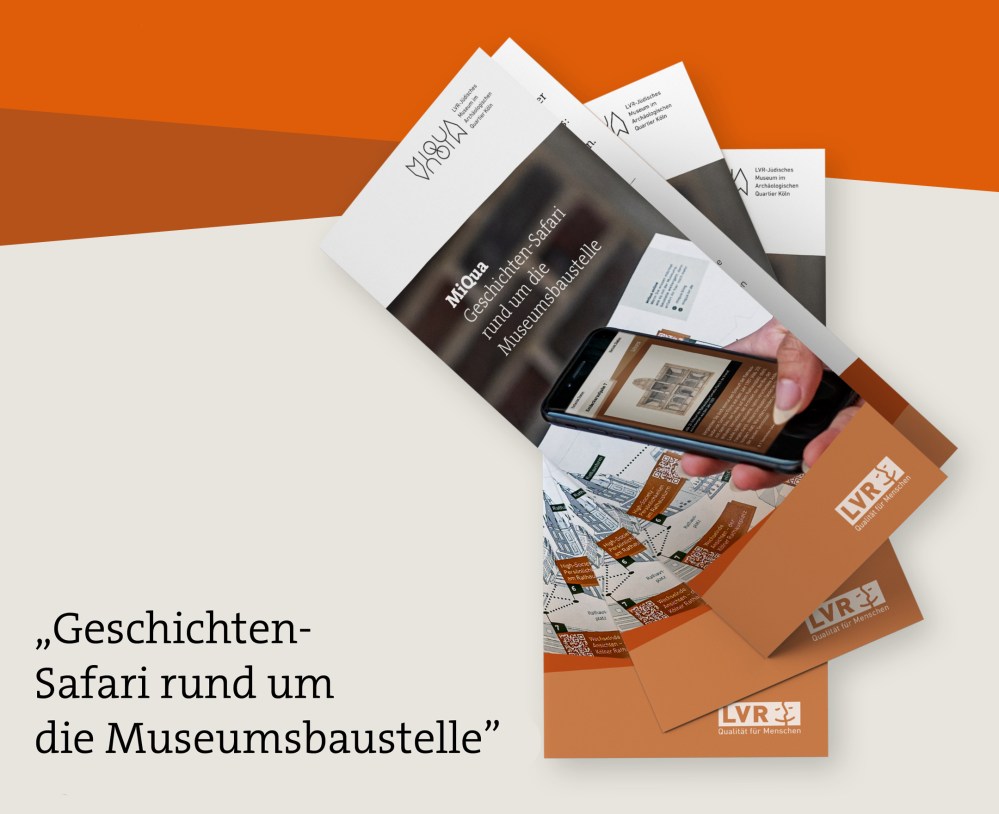 Vor grauem Hintergrund steht unten links folgender Text: "Geschichten-Safari rund um die Museumsbaustelle". Rechts daneben drei übereinanderliegende Flyer mit dem Titel "Geschichten-Safari rund um die Museumsbaustelle". Zu sehen ist eine Hand mit einem Smartphone, vor einem gezeichneten Kölner Rathausturm.