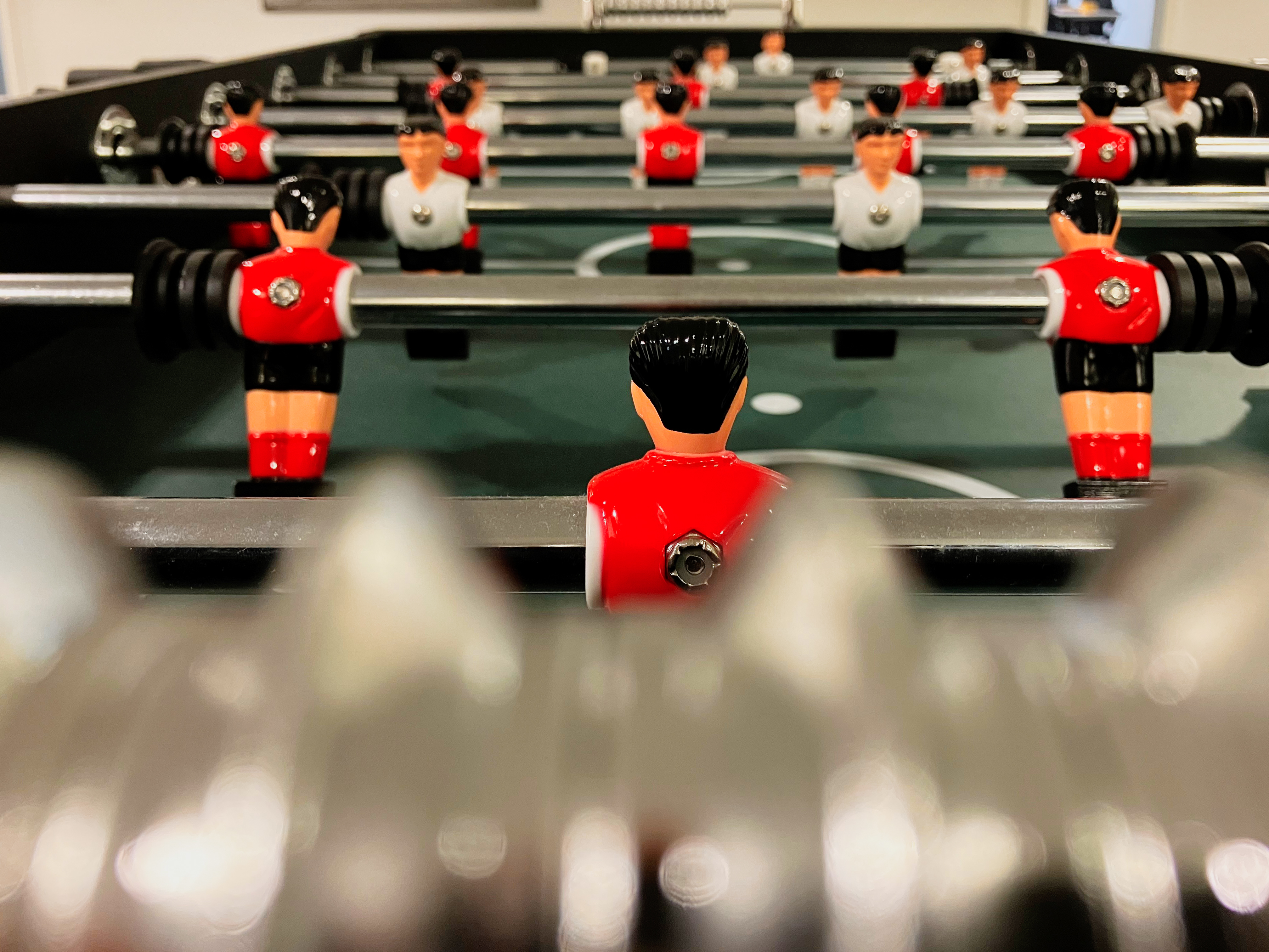 Das Foto zeigt die Aufnahme eines Tischkickers mit Figuren in den Farben weiß und rot aus der Nähe.