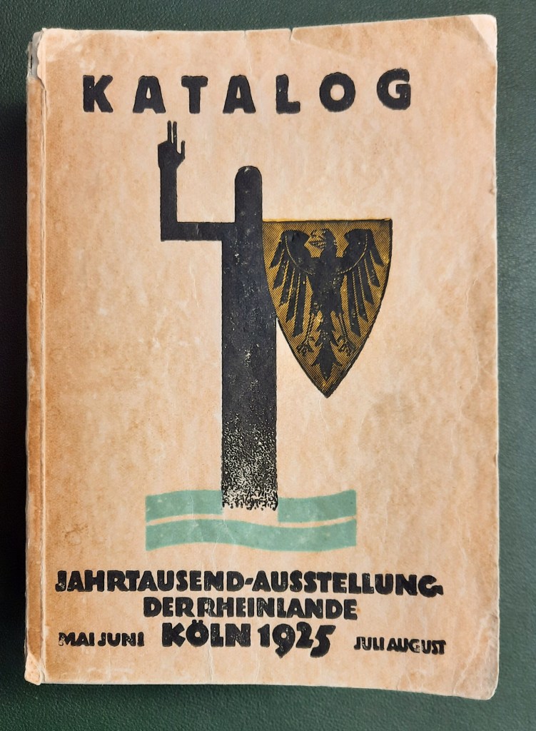 Titelblatt des offiziellen Katalogs zur Jahrtausend-Ausstellung der Rheinlande in Köln, 1925. Das markante Design zeigt eine stilisierte Figur mit erhobener Hand, daneben das Wappen mit dem Reichsadler. Die Gestaltung spiegelt den Zeitgeist der Weimarer Republik wider und unterstreicht den nationalhistorischen Anspruch der Großausstellung, die von Mai bis August 1925 stattfand.