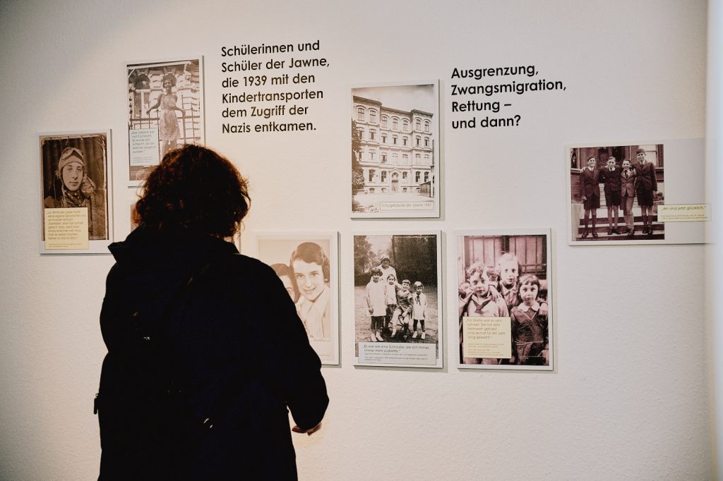 Eine Frau sieht sich historische Fotografien auf einer Ausstellungswand an.